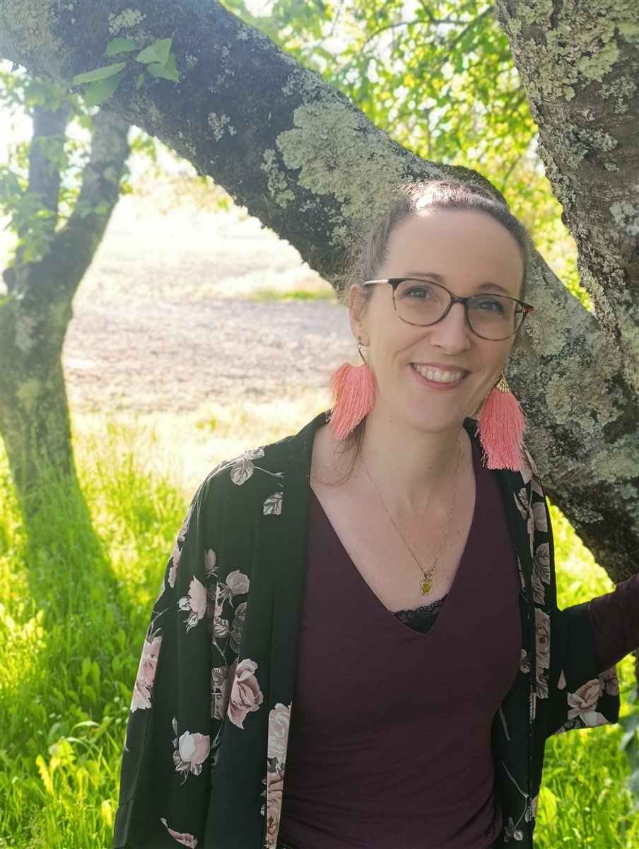 Aurélie, souriante sous un arbre